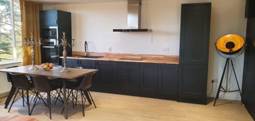 Modern kitchen and dining area in Dublin Exchange Suites villa with black cabinetry, wooden countertop, dining table, and