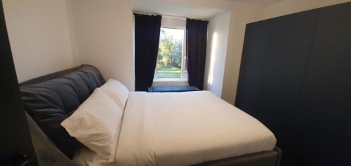 Contemporary bedroom with white bedding, black headboard, and garden view at Dublin Exchange Suites