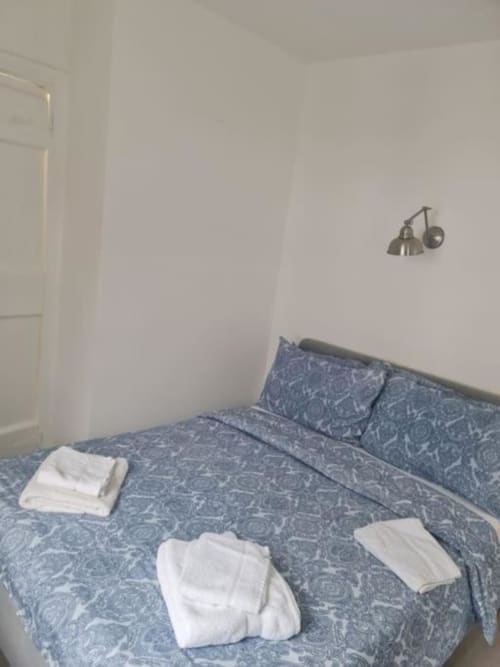 Cosy bedroom at Dublin Exchange Suites cottage with blue patterned bedding, white towels, and wall-mounted lamp.