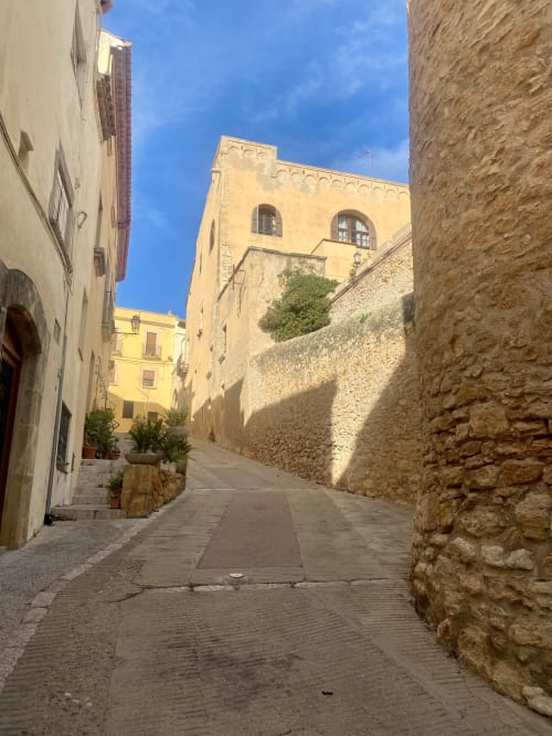 Estrecho callejón de piedra en el pueblo de Altafulla con edificios históricos y cielo azul despejado