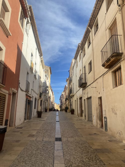 Encantadora calle empedrada en Altafulla con edificios históricos y cielo azul despejado