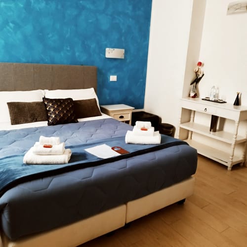 Modern bedroom at AD Trastevere Guest House, Rome with blue accent wall, bed setup with towels, and contemporary furnishings