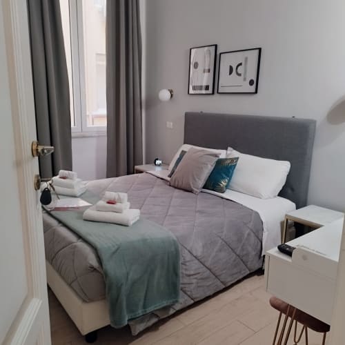 Modern bedroom at AD Trastevere Guest House in Rome with gray headboard, white bedding, folded towels, and city view from