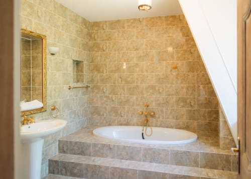 Baño de lujo con bañera ovalada empotrada, azulejos de mármol y cabina de ducha de cristal en la casa rural Domaine de Bize en Mirepoix