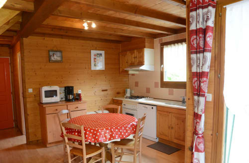 Cuisine et salle à manger chaleureuses du chalet en bois des Gîtes Des Planchettes à Marigny avec nappe à pois rouges