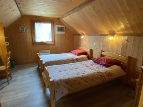 Chambre douillette au grenier du gîte de Marigny avec deux lits en bois et plafond cathédrale