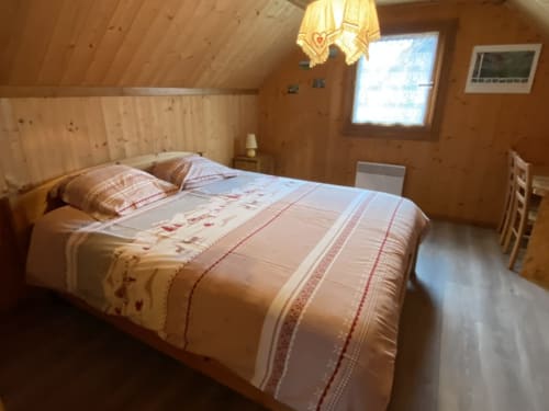 Chambre douillette du chalet en bois aux Gîtes Des Planchettes à Marigny avec literie traditionnelle et vue sur les montagnes