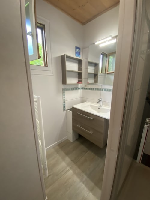 Salle de bain moderne du gîte Chamois aux Gîtes Des Planchettes, Marigny avec lavabo, miroir, rangements et murs carrelés
