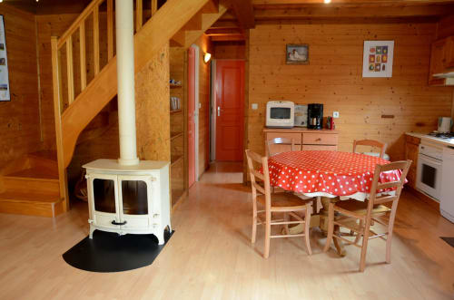 Intérieur douillet du gîte en bois avec table à manger, cuisine, poêle et escalier en bois
