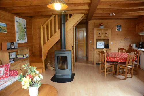 Intérieur douillet du chalet en bois des Gîtes Des Planchettes à Marigny avec poêle, table à manger et mobilier rustique