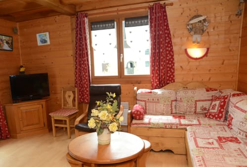 Chambre cosy de chalet alpin avec literie à motifs rouges, boiseries et TV aux Gîtes Des Planchettes à Marigny