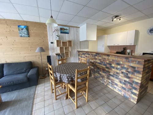 Séjour du gîte aux Planchettes avec kitchenette, table à manger, canapé et mobilier en bois à Marigny, France