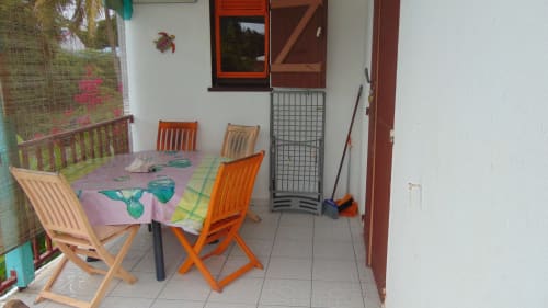 Terrasse de la maisonnette Caribgites à Sainte-Anne avec chaises en bois et nappe rose, vue sur le jardin