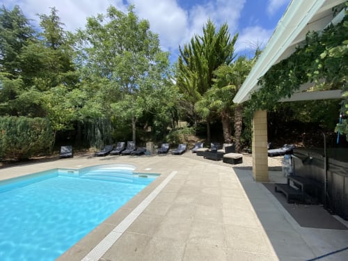 Luxury pool area at Domaine de Bize in Mirepoix with loungers, manicured gardens, and covered terrace overlooking resort