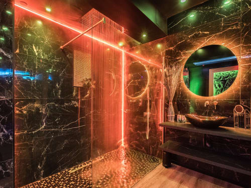 Salle de bains luxe moderne à L'Insolite Spa à Toulouse avec éclairage néon rouge, murs en marbre noir et miroir rond