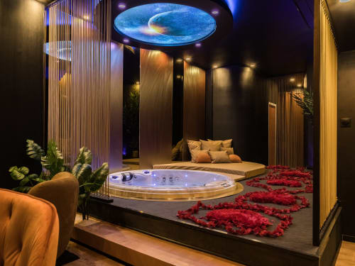 Suite spa luxueuse à L'Insolite à Toulouse avec bain à remous illuminé, pétales de roses, lit et éclairage ambiant