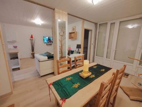 Coin repas cosy à Location MarjoRI : table en bois, chaises, chemin de table vert et décor style chalet montagnard