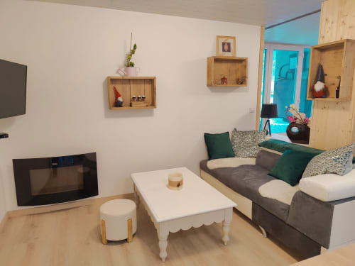 Salon confortable de l'appartement à Location MarjoRI au Lauzet-Ubaye avec canapé gris, table basse blanche, cheminée et montagne