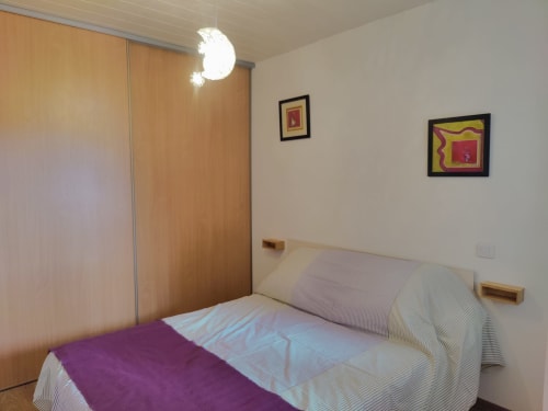 Chambre moderne à Location MarjoRI au Lauzet-Ubaye avec penderie en bois, lit double et tableaux muraux encadrés
