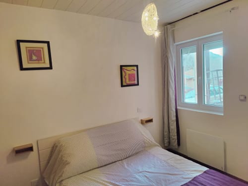 Chambre moderne lumineuse à Location MarjoRI avec vue sur les montagnes, literie rayée, éclairage suspendu et tableaux encadrés