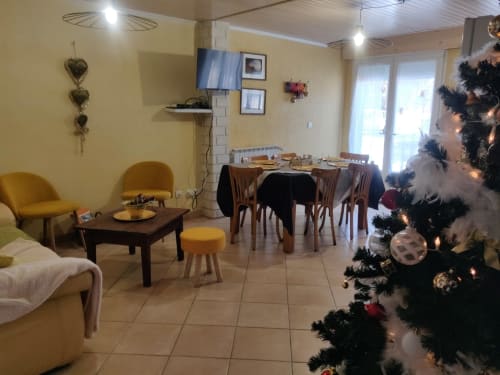 Salon cosy de l'hôtel Marjori au Lauzet-Ubaye avec sapin de Noël, coin repas et vue sur les montagnes