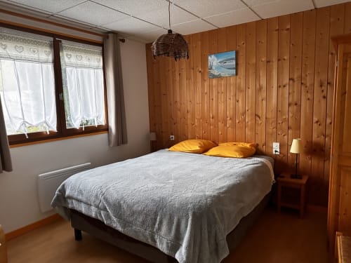 Chambre cosy du gîte Des Planchettes avec lit queen-size, oreillers jaunes et vue sur fenêtre à Marigny