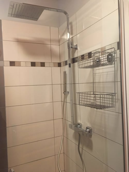 Douche moderne avec carrelage crème, douchette pluie et paniers de rangement en métal au Chalet Le Lynx des Gîtes