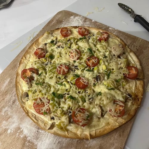 Pizza maison avec tomate, poireau, fromage et herbes sur planche en bois au Château Ségot, Neuilly-le-Réal
