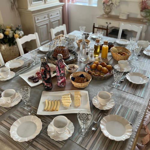 Table de petit-déjeuner élégante au Château Ségot avec viennoiseries, fromage, fruits frais et fine porcelaine