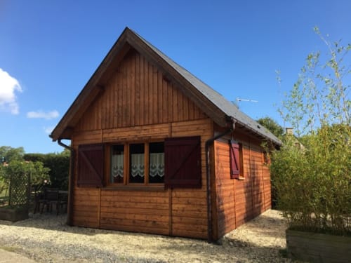 Le chalet Pomme cottage aux Gîtes Les Rainettes, avec sa façade en bois, toit pentagonal et jardin environnant