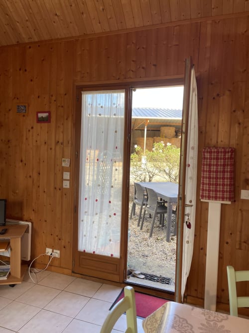 Intérieur de gîte en bois avec portes vitrées ouvertes sur le jardin aux Gîtes Les Rainettes, Vienne-en-Bessin