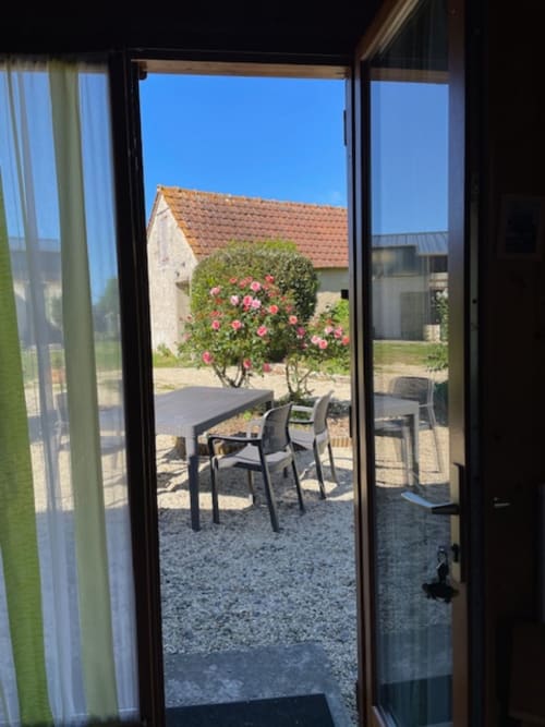 Vue depuis le chalet Rainette aux Gîtes Les Rainettes : terrasse du jardin avec arbustes fleuris et paysage champêtre