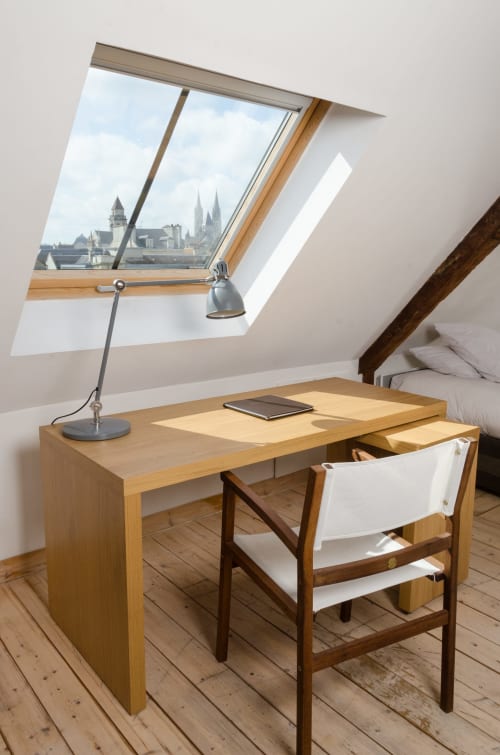 Loft aménagé à Caen avec puits de lumière dominant la cathédrale, bureau en bois, lampe et chaise
