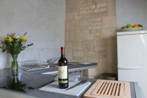 Comptoir de cuisine moderne du Loft Fraternité avec bouteille de vin, fleurs et dosseret en pierre à la Villa République Normandie, Caen