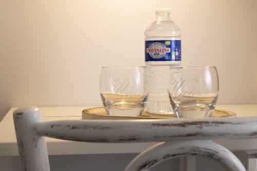Bouteille d'eau Cristaline et verres sur plateau en bois dans la chambre twin standard de l'Hôtel De Lion Sur Mer