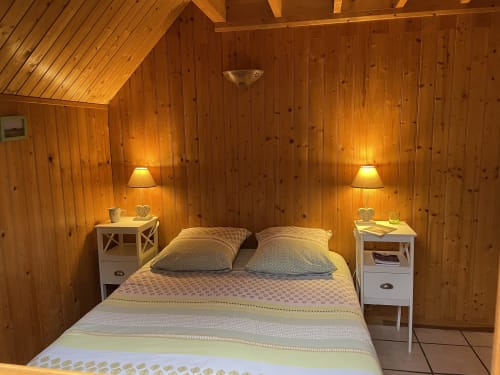 Chambre douillette du gîte Les Rainettes avec lit queen-size, tables de nuit blanches et éclairage chaleureux
