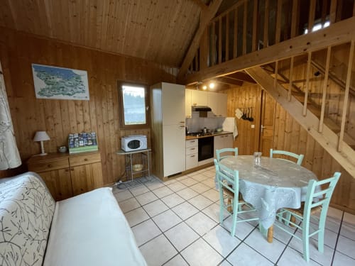 Intérieur douillet de gîte en bois avec cuisine, salle à manger et chambre aux Gîtes Les Rainettes à Vienne-en-Bessin