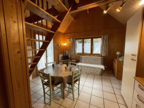Intérieur douillet du gîte Les Rainettes : table à manger, lit et vue sur le jardin à Vienne-en-Bessin