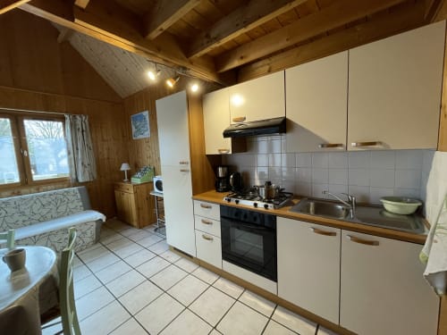 Cuisine spacieuse du gîte Les Rainettes avec électroménagers modernes, poutres en bois et vue sur le jardin à Vienne-en-Bessin