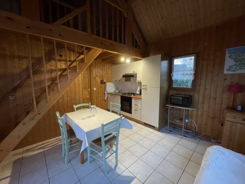 Cuisine rustique avec chaises bleues, électroménagers crème et mezzanine aux Gîtes Les Rainettes