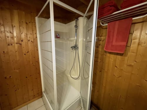 Douche moderne avec cadre blanc et portes en verre dans la salle de bain rustique des Gîtes Les Rainettes