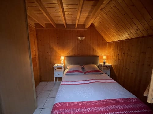 Chambre douillette aux boiseries chaleureuses au gîte Le chalet Pomme des Gîtes Les Rainettes, avec lit double et lampes de chevet