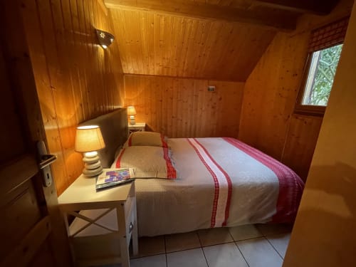 Chambre cosy du gîte Les Rainettes : lit double, lampe de chevet et fenêtre donnant sur le jardin.
