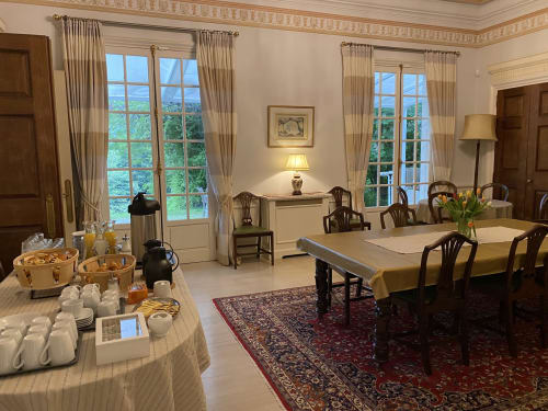 Elegante comedor del Domaine de Bize con vistas al jardín, mesa de conferencias y decoración clásica en Mirepoix