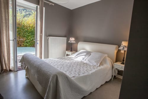 Chambre lumineuse aux Chambres d'hôtes Les Pratges à Figeac avec lit queen, vue sur le jardin par portes-fenêtres et décor moderne