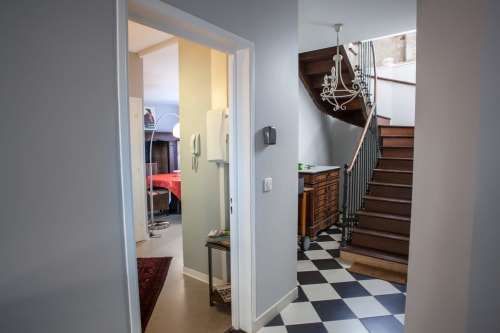 Couloir moderne du gîte Les Pratges à Figeac avec carrelage à damier, escalier en bois et entrée chambre