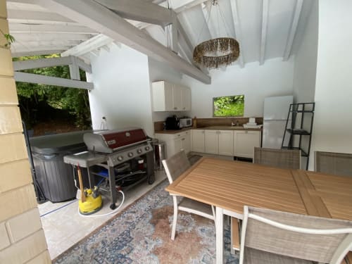 Cuisine extérieure moderne et espace repas au Domaine de Bize à Mirepoix avec barbecue, électroménagers en acier inoxydable et bois