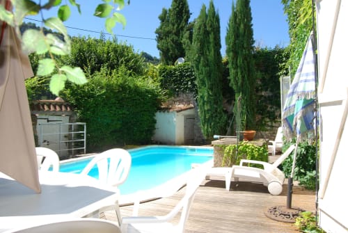 Piscine turquoise avec transats blancs, terrasse et murs couverts de lierre aux Chambres d'hôtes Les Pratges à Figeac