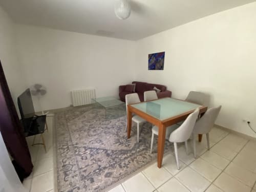 Spacious living room with dining table and burgundy sofa at Domaine de Bize Mirepoix, Ariège France