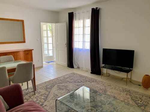 Spacious living room in Carcassonne apartment at Domaine de Bize with TV, seating, and access to garden views
